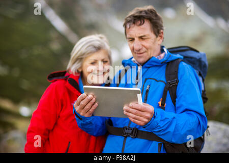 Senderismo Senior pareja utilizando app o mapa de viaje en tablet durante la caminata. Foto de stock