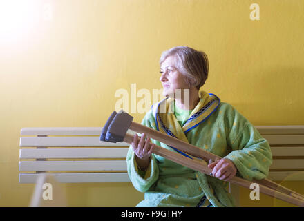 Mujer mayor con muletas sentado en un banco Fotografía de stock - Alamy