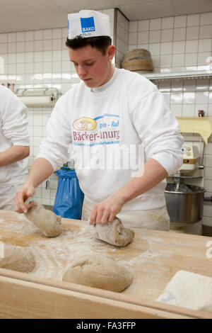 Aprendiz de panadero amasa pan masa. Foto de stock