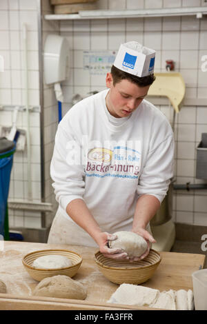 Aprendiz de panadero amasa pan masa. Foto de stock