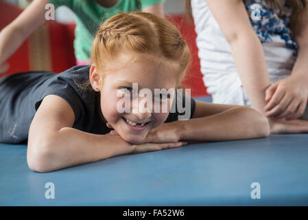 Chica acostada en colchoneta de ejercicios en el gimnasio de la escuela de Baviera, Múnich, Alemania