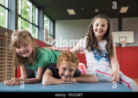 Las niñas descansando sobre una esterilla para hacer ejercicio en la sala de deportes, Baviera, Munich, Alemania