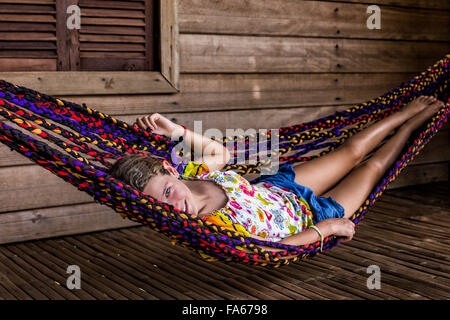 Chica tumbado en una hamaca en la terraza de madera Foto de stock