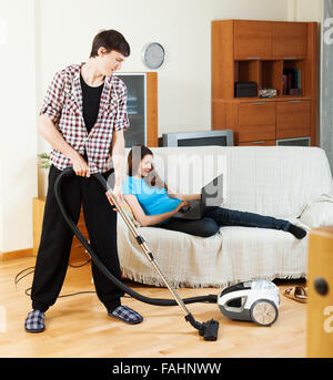 Hombre joven limpieza de sofá con aspiradora en dejar habitación en casa