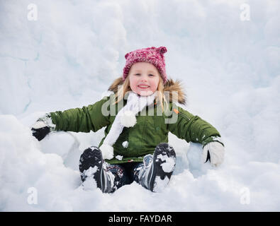 Invierno afuera puede ser cuento de hadas-maker para niños o adultos. Niño feliz en verde cubra sentado en la nieve. Foto de stock