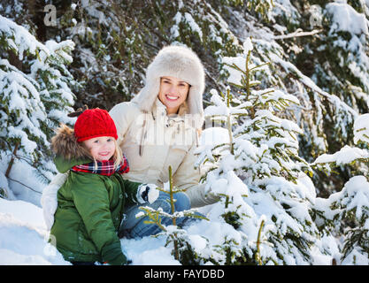 Invierno afuera puede ser cuento de hadas-maker para niños o adultos. Feliz madre e hijo al aire libre entre los abetos nevados Foto de stock