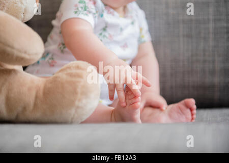 Niña (12-17 meses) que sujetan el pie