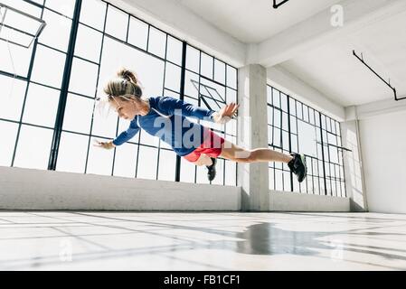 Ángulo de visión baja de la mujer joven en el gimnasio haciendo subir el aire.