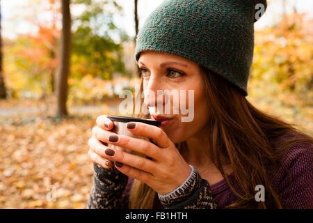 Mujer joven bebiendo café en otoño bosque