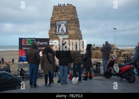 La gente ve una gran hoguera de Año Nuevo que se está construyendo en la playa Scheveningen Foto de stock