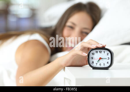 Niña alegre despertar en la mañana apagar el despertador en su habitación