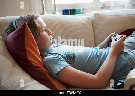 Suecia, Boy (12-13) tumbado en el sofá y jugar juegos de video