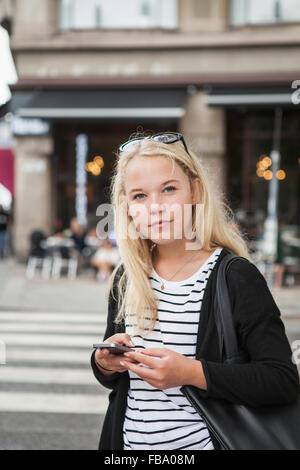 Suecia, Skane, Malmo, adolescente (14-15) usando el teléfono inteligente en la calle