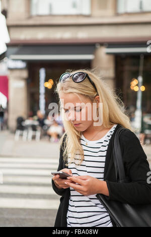 Suecia, Skane, Malmo, adolescente (14-15) usando el teléfono inteligente en la calle