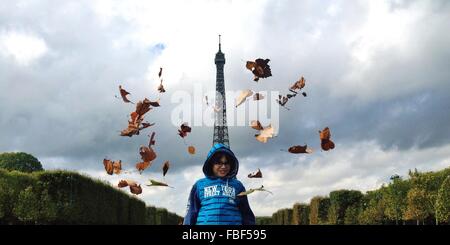 Ángulo de visión baja de muchacho de pie contra la Torre Eiffel