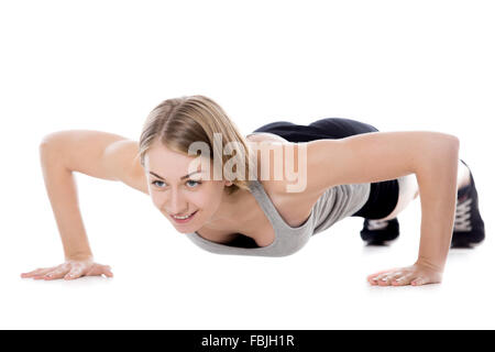 Retrato de joven bella mujer slim haciendo ejercicios físicos en la alfombrilla, calentando, Push-ups, longitud completa aislada de imagen studio Foto de stock