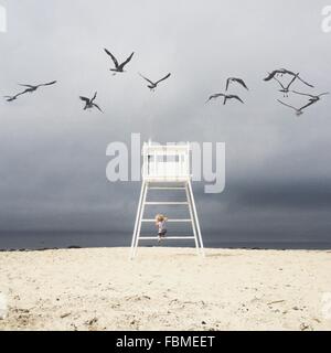 Niño subiendo silla salvavidas en la playa, california, Estados Unidos
