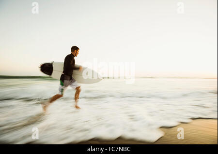 Hombre caucásico llevar tablas de surf en la playa