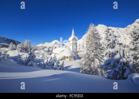 El sol de invierno ilumina el paisaje nevado y la típica iglesia, Maloja, Engadin, Cantón de Graubunden, Suiza