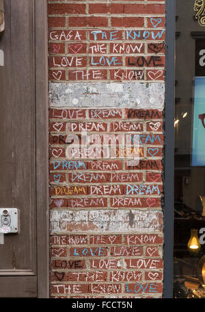 La tiza de color pintadas en un muro de ladrillo rojo con las palabras de amor, el sueño, y el saber en el exterior de una tienda. Foto de stock