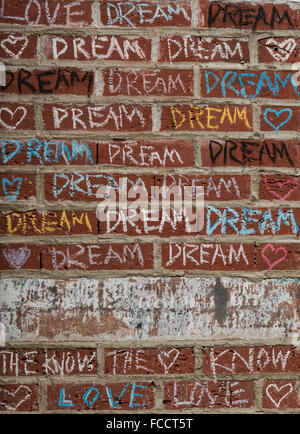 La tiza de color pintadas en un muro de ladrillo rojo con las palabras de amor, el sueño, y el saber en el exterior de una tienda. Foto de stock