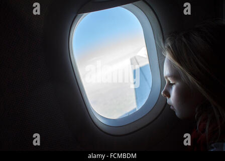 Niña mirando por la ventana del avión mientras avión está volando.