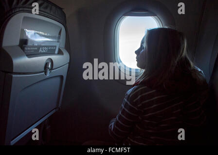 Niña mirando por la ventana del avión mientras avión está volando.