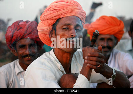 Rajasthani camelleros fumar chillum, con turbante naranja , en Pushkar, Rajastán Foto de stock