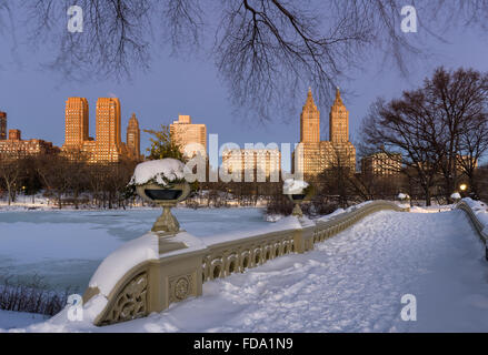 Central Park Bow Bridge en el lago y el Upper West Side de edificios al amanecer en una helada mañana de invierno. La Ciudad de Nueva York