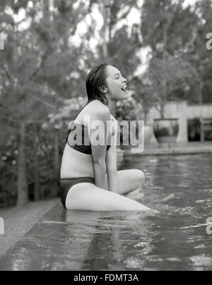 Una mujer se sienta en la cornisa de la piscina infinity en la Granja de San Benito, Filipinas. Foto de stock