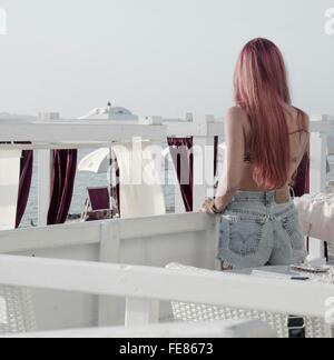 Vista trasera de una mujer mirando el mar desde el restaurante