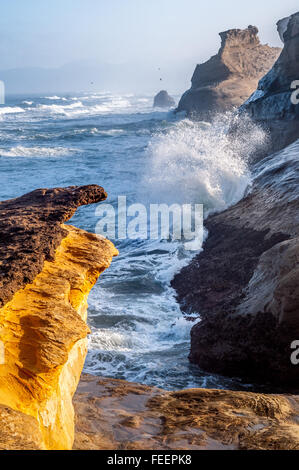 Sol de la mañana arroja luz dorada en los acantilados de arenisca como las olas rompen en la distancia. Foto de stock