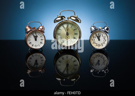 Vintage relojes de alarma mostrando cinco minutos a doce, fondo azul Foto de stock