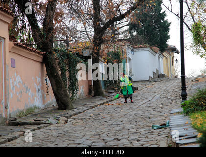 Mujer barrer la calle de adoquines en el casco antiguo de la ciudad de Plovdiv, Bulgaria, Europa oriental Foto de stock