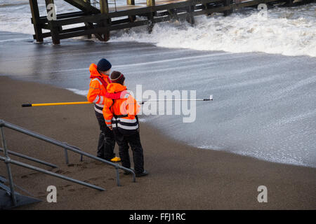 Dos científicos ambientales tomando muestras de la calidad del agua en el mar frente a la playa en Aberystwyth en la costa oeste de Gales. El agua del río ha sido etiquetados con bacteriófago y su distribución y dilución en el mar se mide cada 60 minutos durante 48 horas Foto de stock