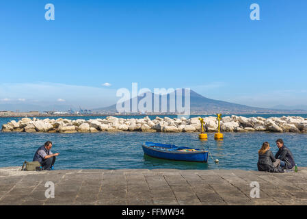 Bahía de Nápoles, vista de la gente que se relaja a lo largo de la costa en la Bahía de Nápoles con el Monte Vesubio visible en la distancia, Nápoles, Italia.