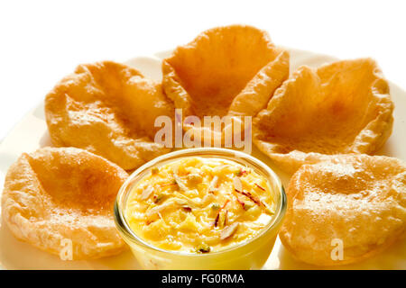 Postre indio kesar azafrán shrikhand yogur cremoso servido en un tazón y Puri en placa Foto de stock