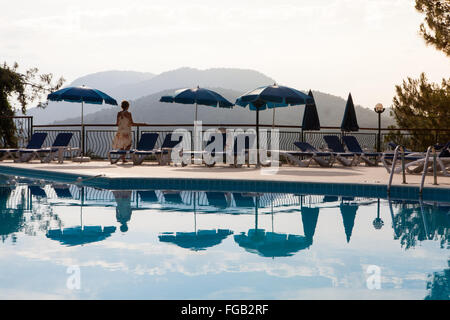 Una mujer está mirando las vistas desde el balcón al lado de la piscina, Turquía.