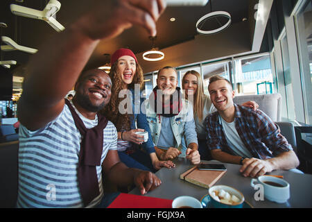 Grupo de amigos adolescentes haciendo selfie alegres en cafe Foto de stock