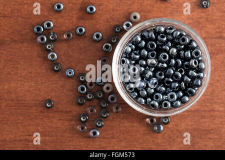 Gris brillante perlas de semilla en un pequeño recipiente y sobre tabla, visto desde arriba. Foto de stock