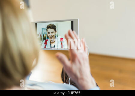 Mujer mirando senior en la imagen de la joven en tableta digital