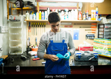 En su taller mecánico poner guantes de trabajo Fotografía de stock - Alamy