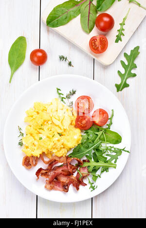 Desayuno con huevos revueltos, bacon y ensalada de verduras, vista superior