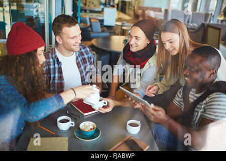 Chicos y chicas amable tomando té y charlando en el café Foto de stock