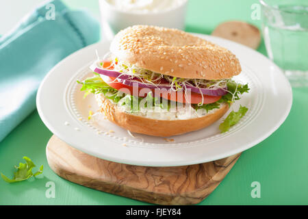 Sándwich de tomate en bagel con queso crema de lechuga cebolla brotes de alfalfa