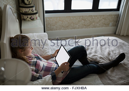 Adolescente utilizando tablet digital en la cama