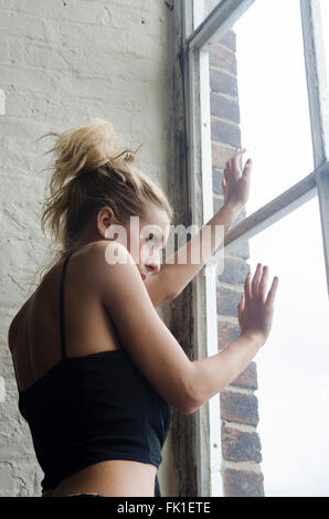 Asustada mujer mirando por la ventana