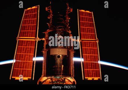 El Telescopio Espacial Hubble atracados en el compartimiento de carga del Transbordador Espacial Columbia, mientras el sol se eleva dando el observatorio flotante un profundo halo naranja el 3 de marzo de 2002, en la órbita de la tierra. Foto de stock
