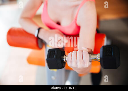 Primer plano de metal pesa mantenido por el joven deportista en rosa en el gimnasio de capacitación superior Foto de stock