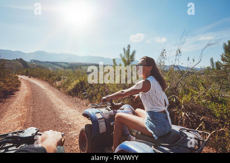 Mujer joven en quad por un sendero. Mujer joven de conducción de vehículos todo terreno en la naturaleza en un día soleado. Foto de stock